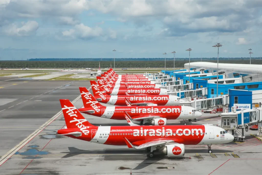 Planes lining up in a row at the airport sporting the Air Asia logo, a company that applied the blue ocean strategy in Malaysia.