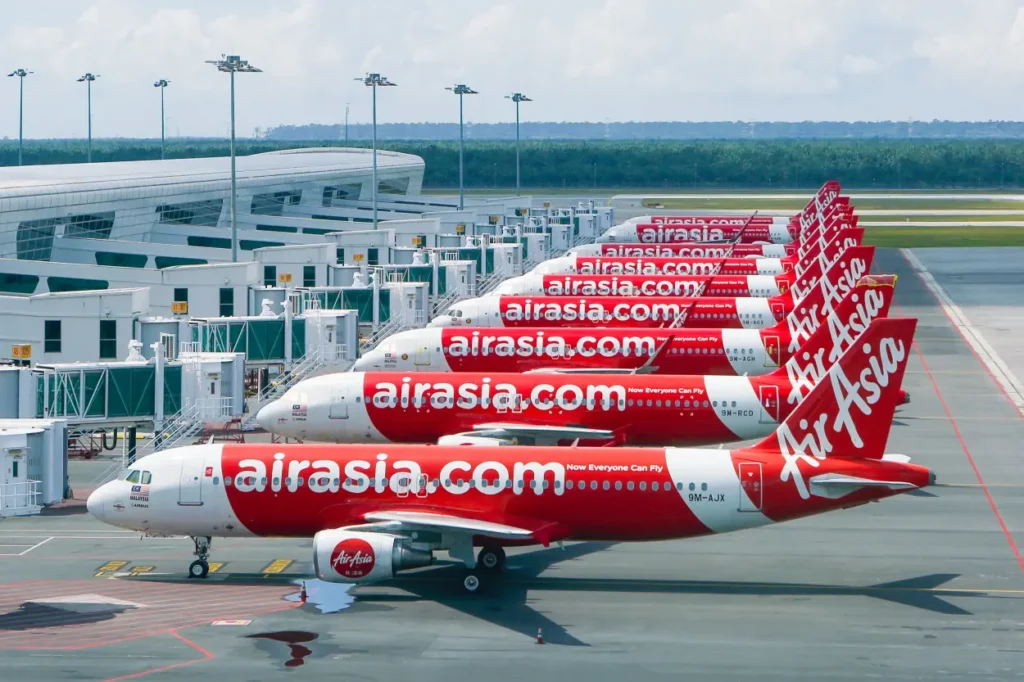 Planes lining up in a row at the airport sporting the Air Asia logo, a company that applied the blue ocean strategy in Malaysia.