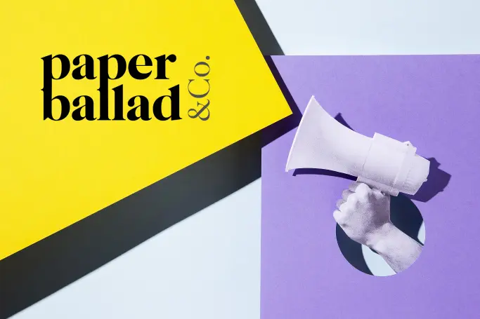 A hand holding megaphone with a paperballad's brand logo to signify achieving brand awareness.